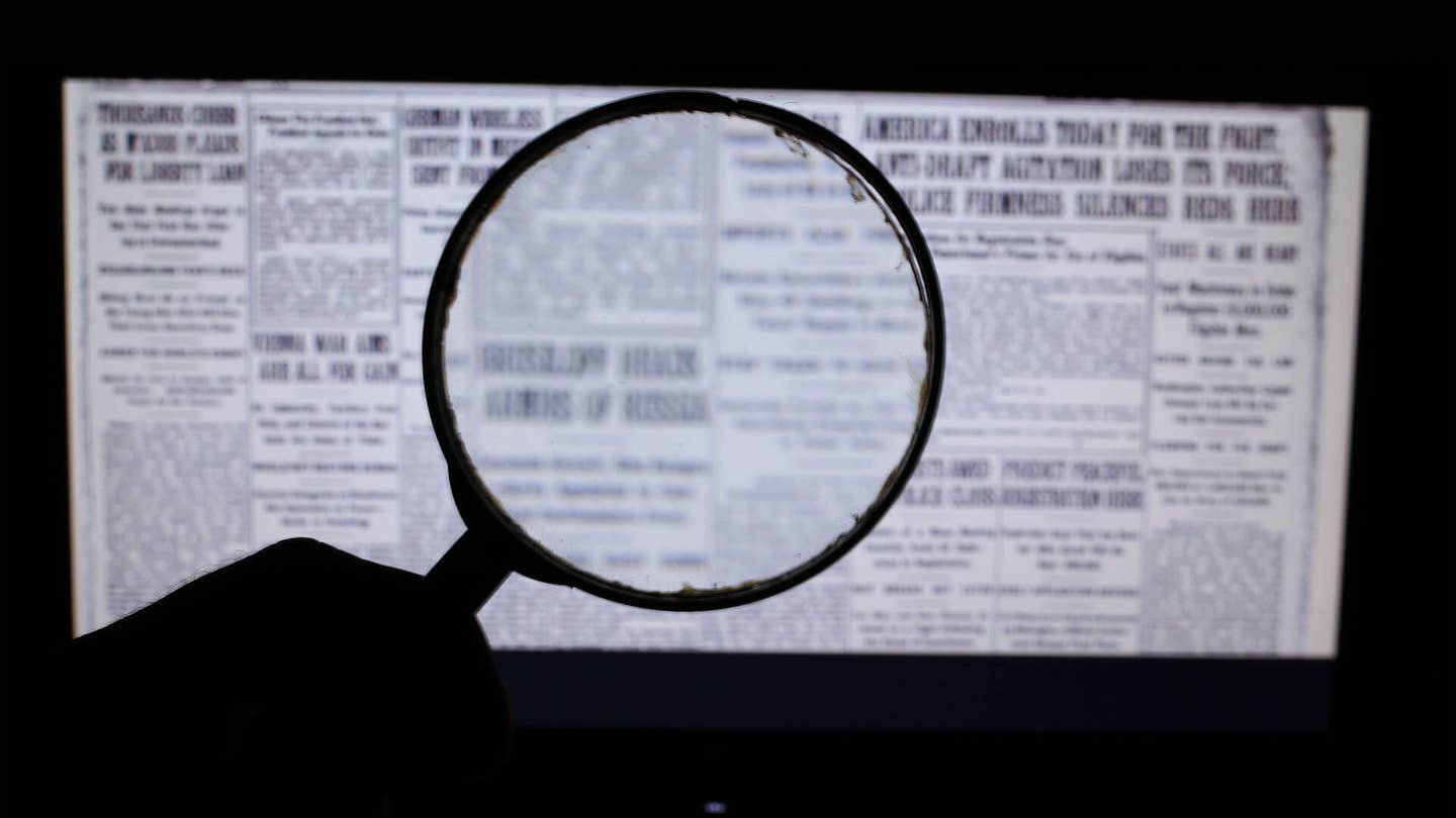 hand holding magnifying glass for fake news on laptop screen artificial intelligence