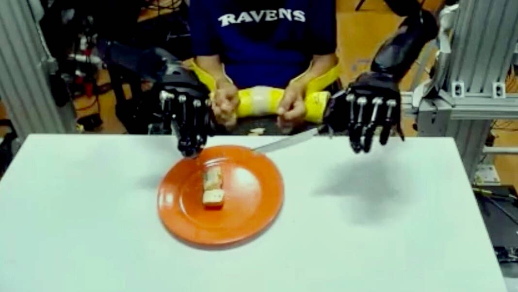 paralyzed man with robot arms eating cake fork knife