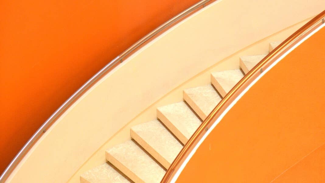 tech stories cream colored twisting staircase orange walls