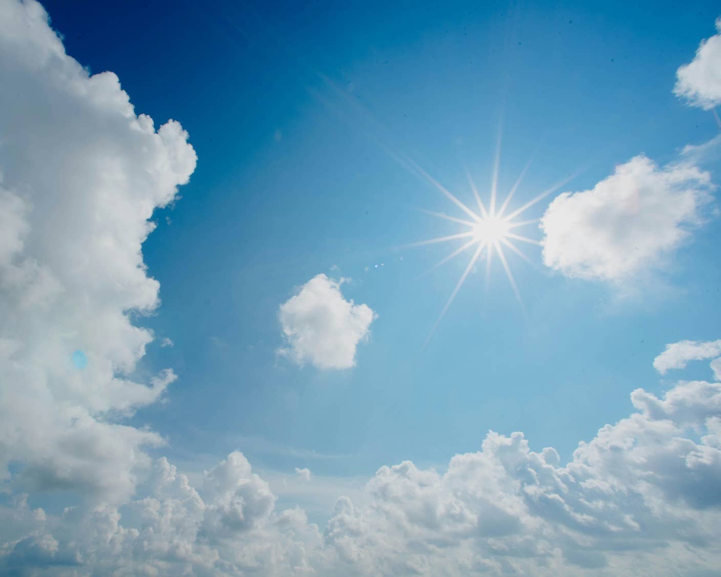 The sun shines on white clouds and blue sky