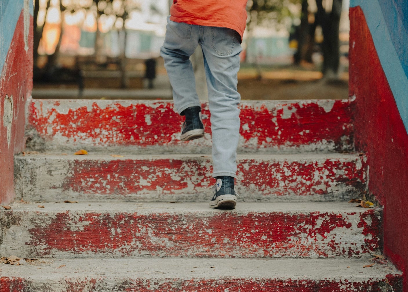 A kid walks up red painted stairs in high tops