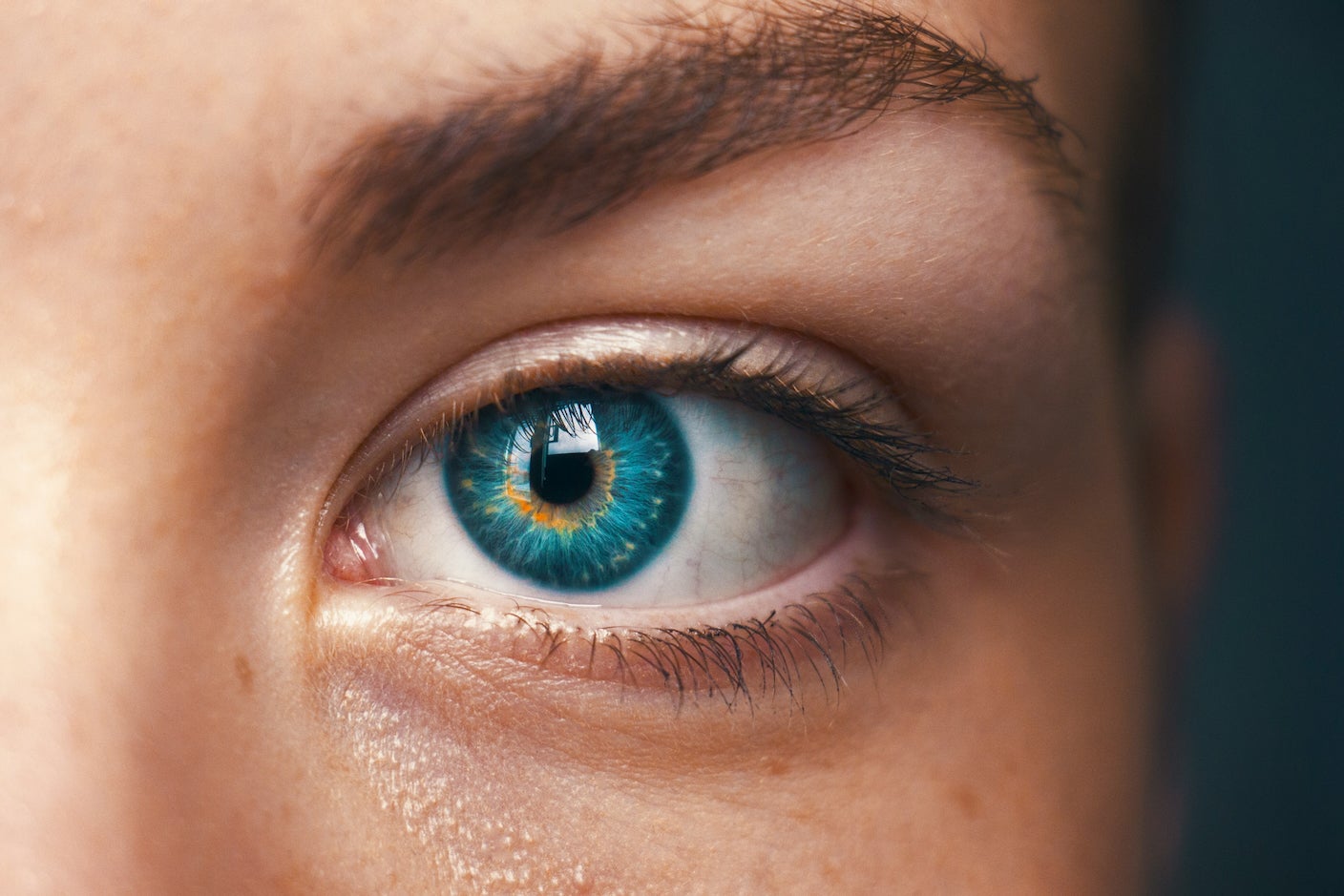 A close-up photo of a blue eye with orange highlights