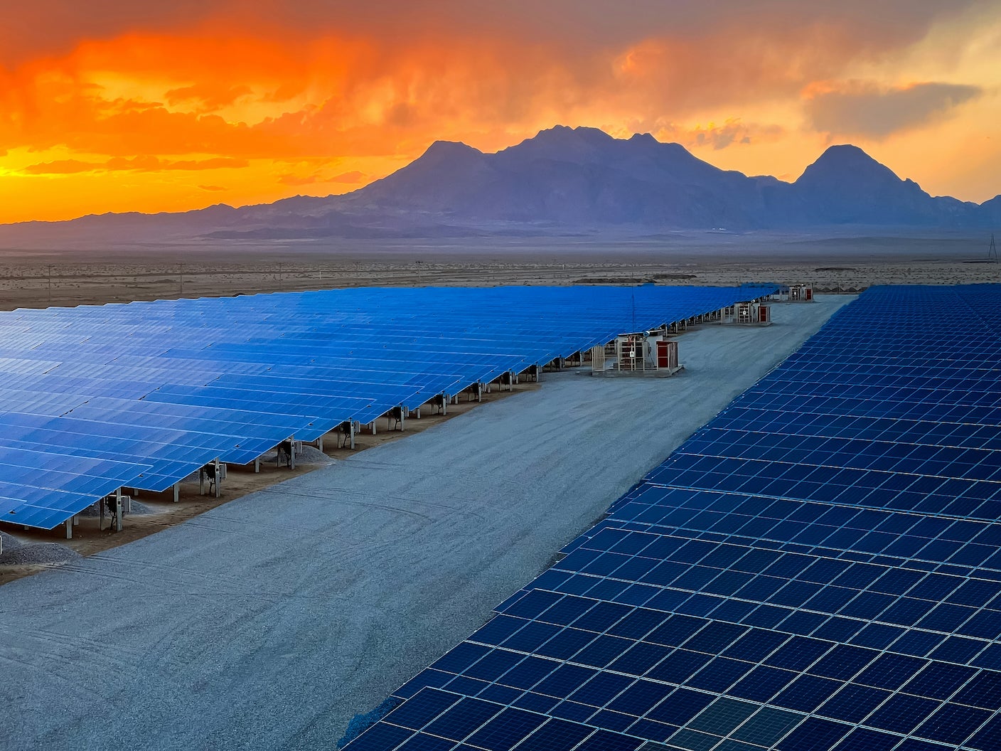 A solar panel installation in the desert at sunset.