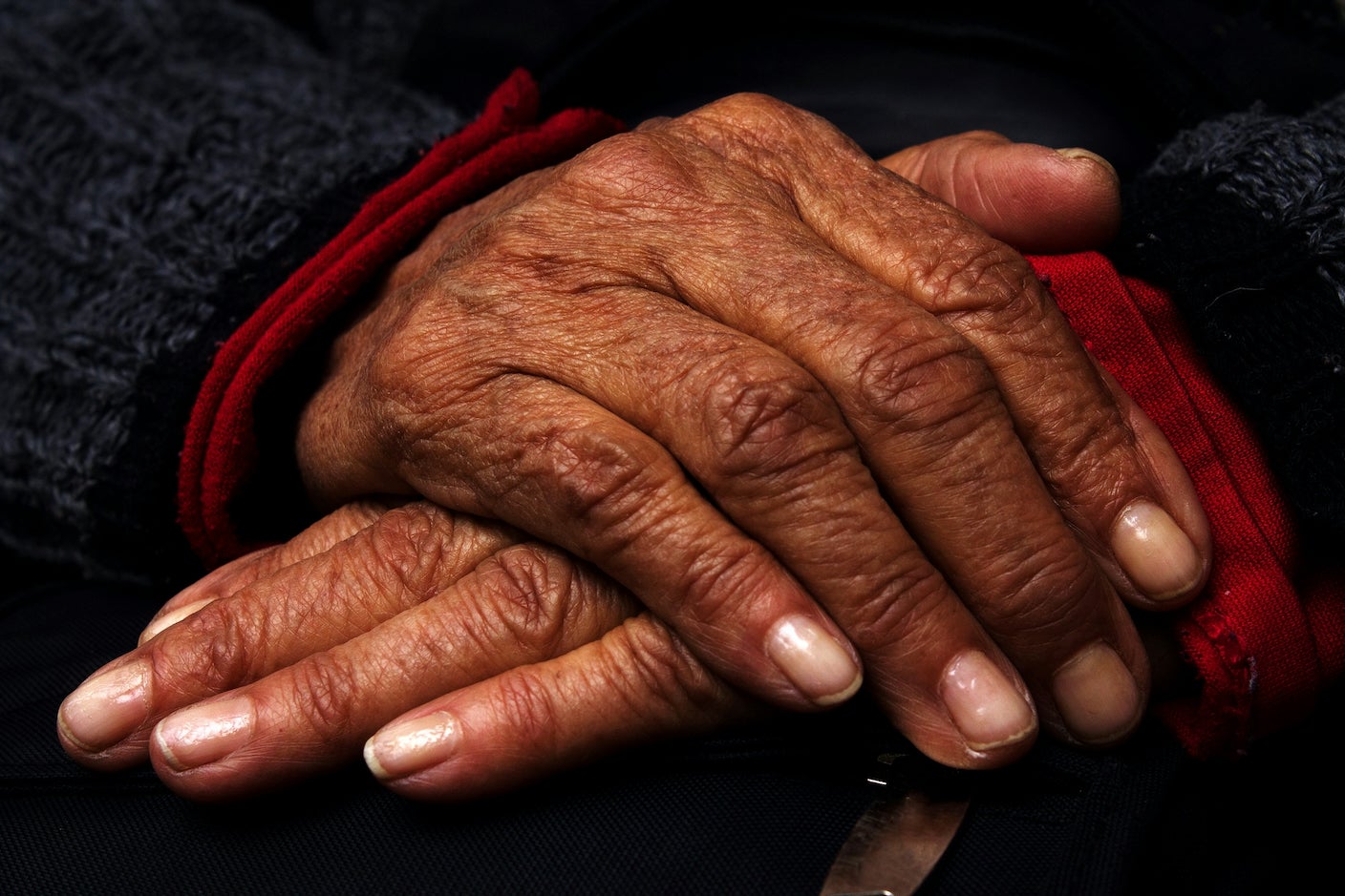 Hands resting on one another in blue sweater with red cuffs