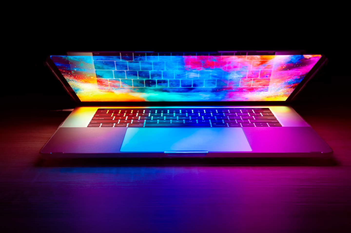 Hackers Are Automating Cyberattacks With AI. Defenders Are Using It to Fight Back. A half open laptop with a colorful display in a darkened room