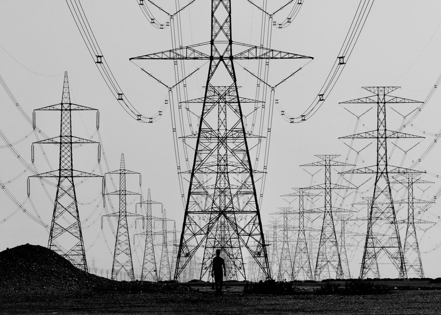 A person is silhouetted against power lines marching into distance.