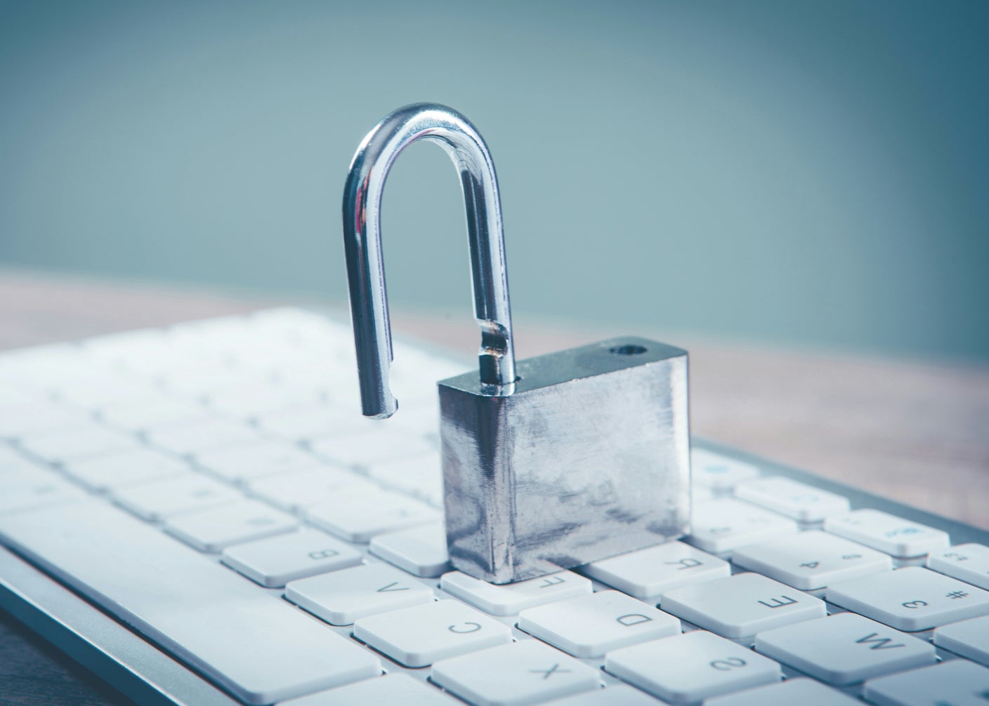 A silver padlock sits on a computer keyboard unlocked