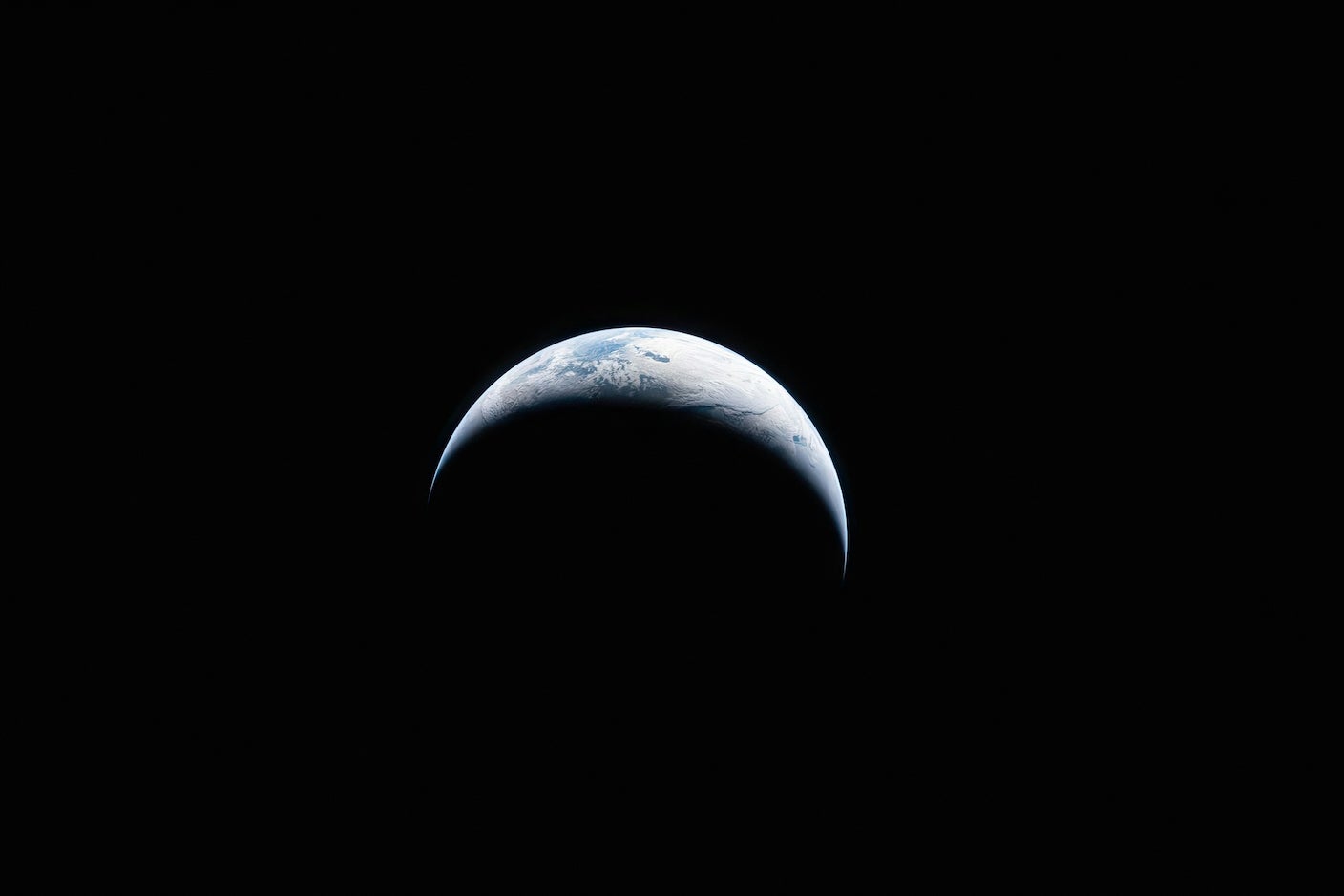 Earth illuminated against the blackness of space. Photo taken by an Artemis II crew member through Orion spacecraft window.