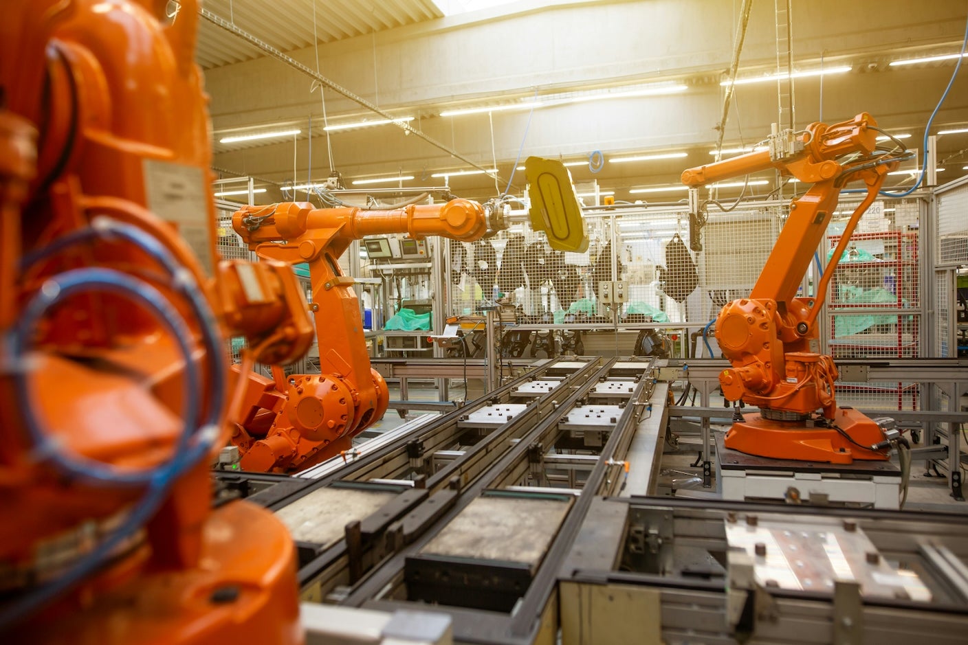 Orange robotic arms work in a factory