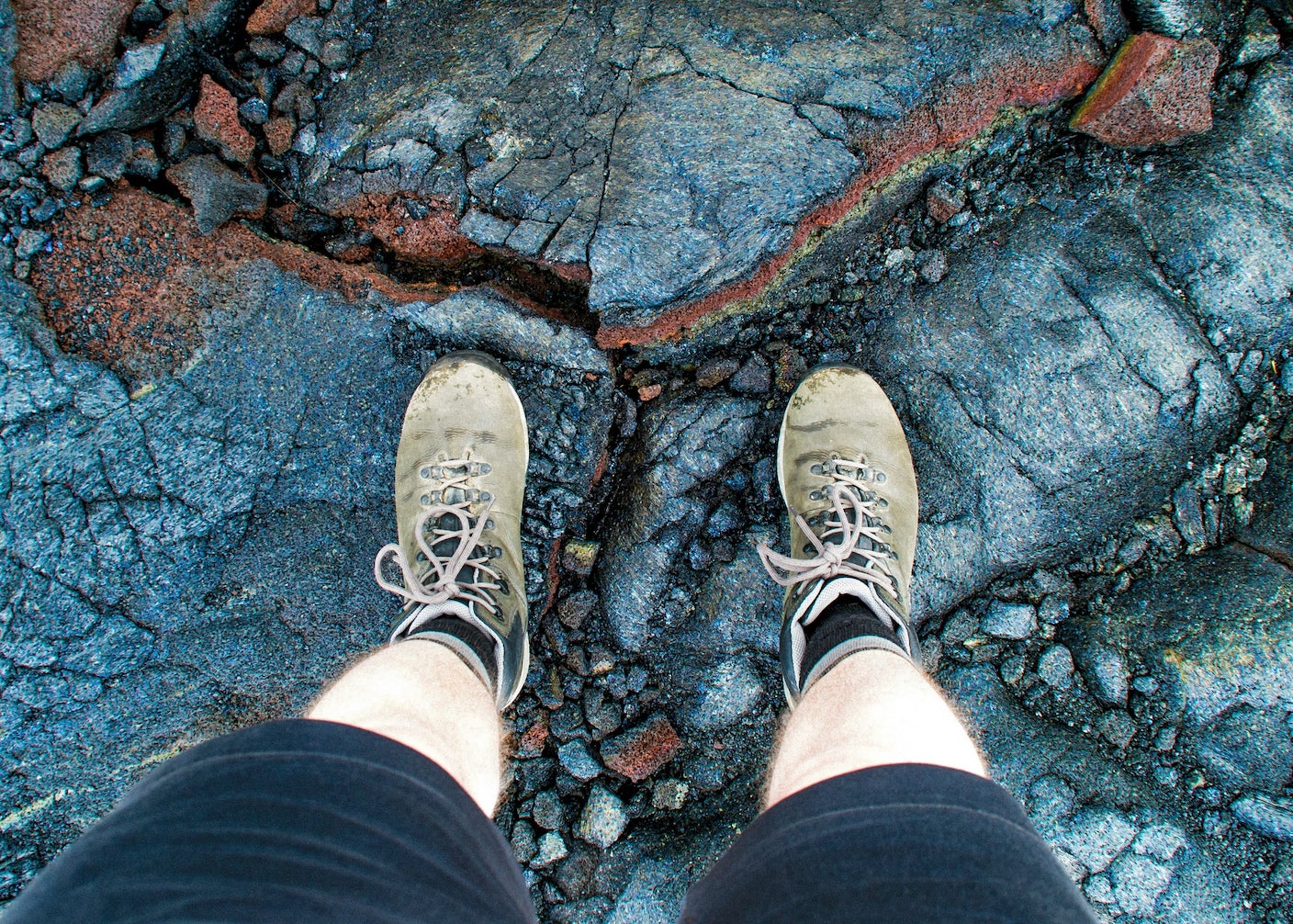 A person wearing hiking boots is standing on colorful stone.
