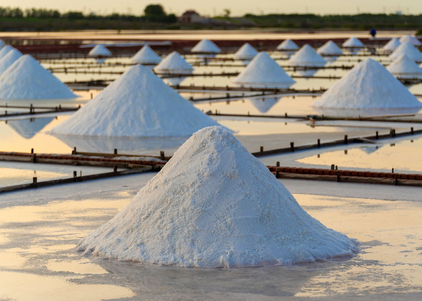 Piles of salt in evaporation pools disappear into the distance