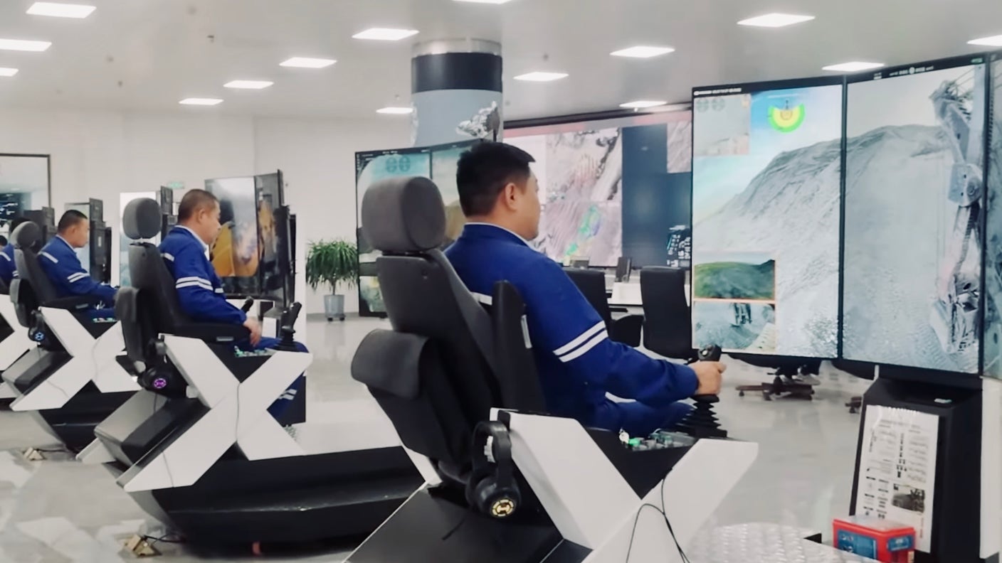 A line of workers at video-game-like terminals