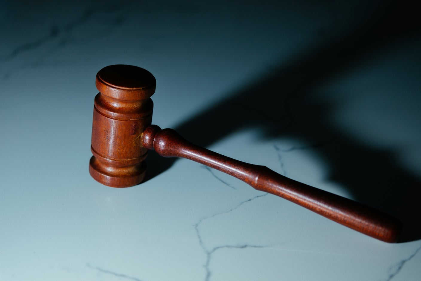 A wooden judge's gavel sits on a marble table
