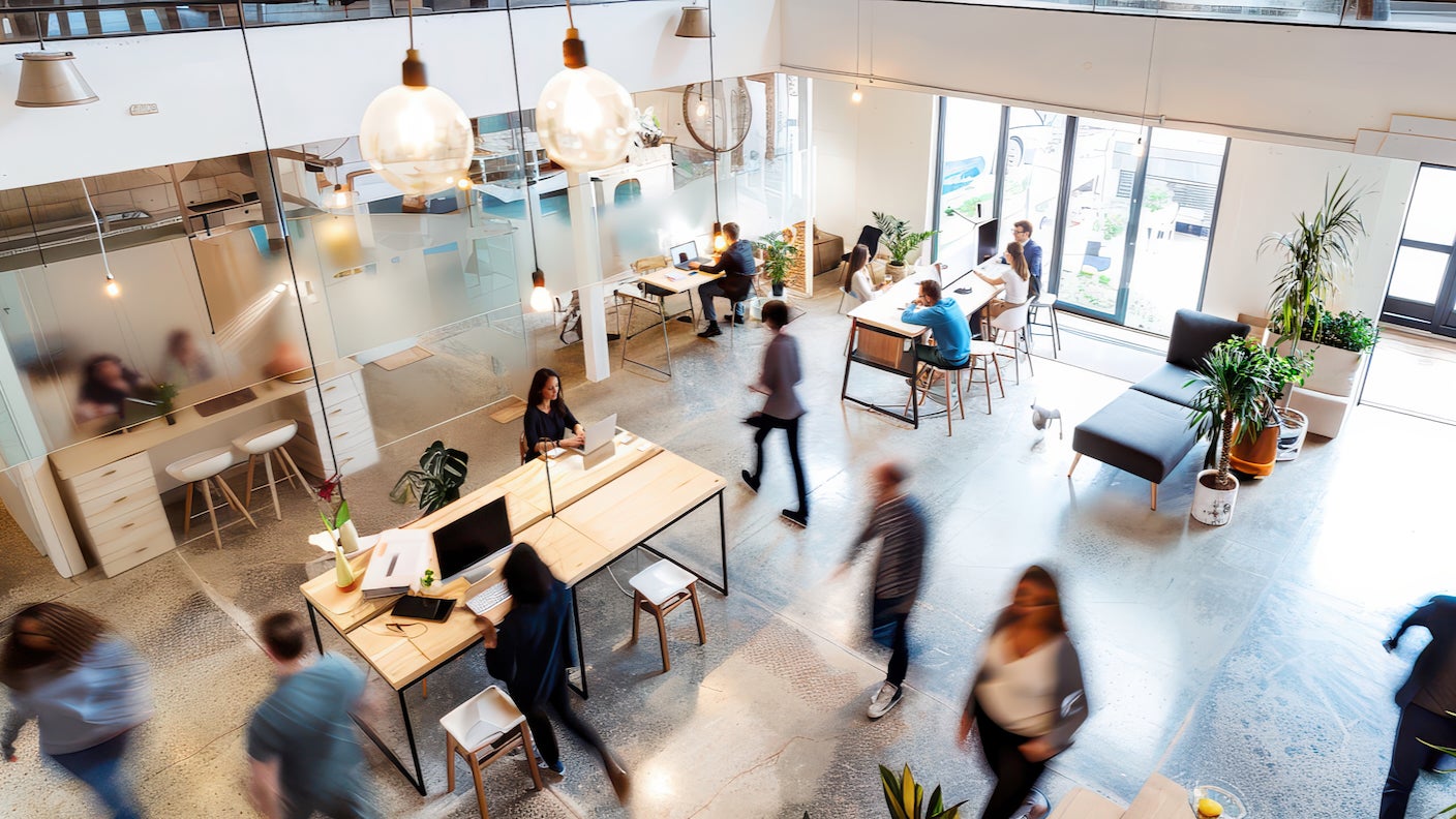 Workers in a modern office space on laptops and walking