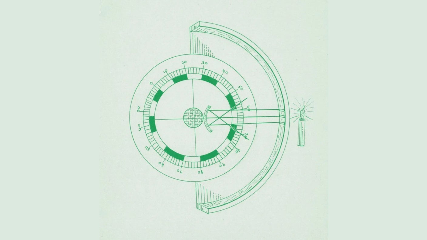 A scientific instrument to measure light sits next to a series of circular holes with a tree in the background.