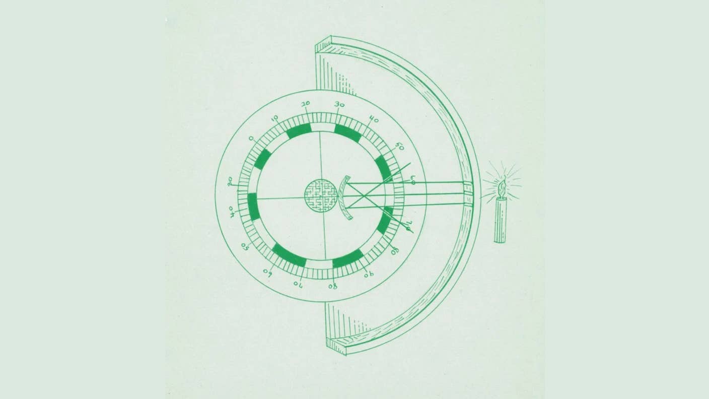 A scientific instrument to measure light sits next to a series of circular holes with a tree in the background.