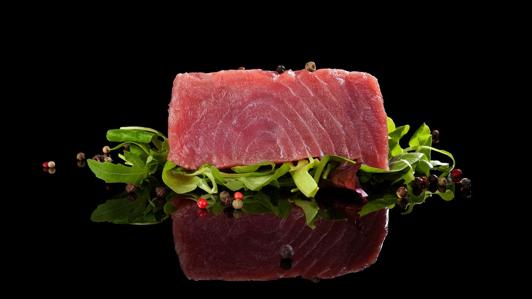 tuna-steak-on-lettuce-black-background-reflection