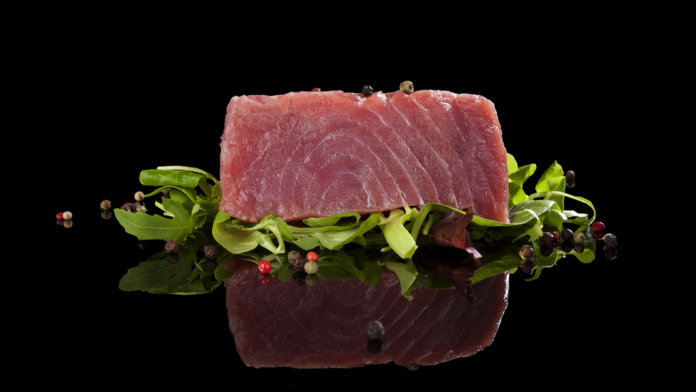 tuna-steak-on-lettuce-black-background-reflection