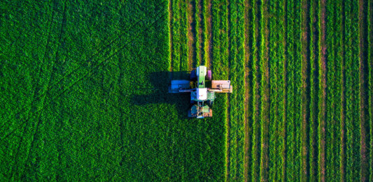 farms-of-the-future-autonomous-robot-tractor-mowing-green-field-aerial-view