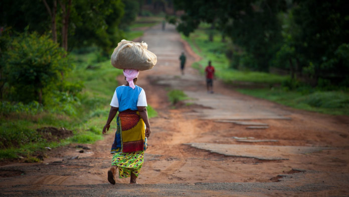 extreme-poverty-free-life-dirt-road-woman-carrying-bundle-on-head