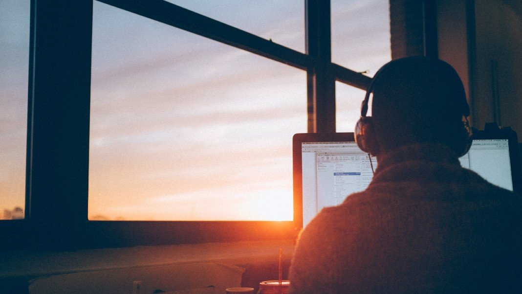 future of work man working in front of computer near a window showing sunset