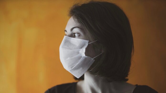 vaccine human challenge trials coronavirus pandemic woman in mask yellow background