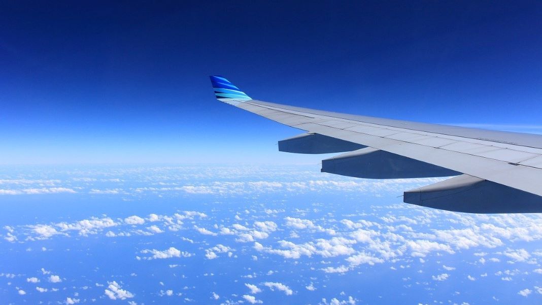 plane wing in blue sky jet fuel emissions